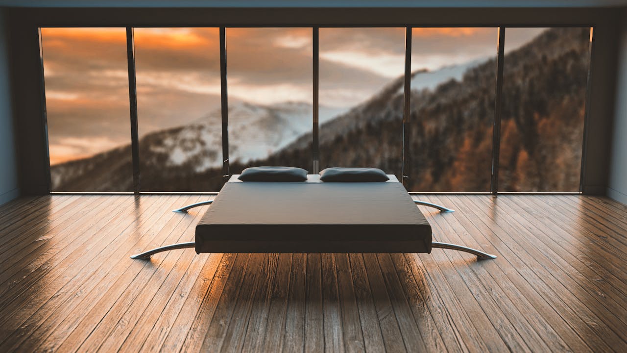 our-story Minimalist bedroom with large windows offering a breathtaking mountain view during sunset.